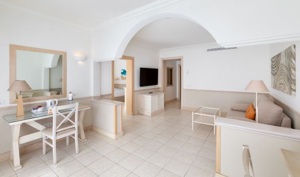 Living area of the Gold Level Gran Suite with sofa, television, table and chairs