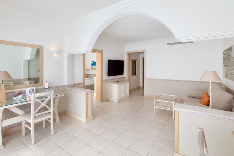Living area of the Gold Level Gran Suite with sofa, television, table and chairs